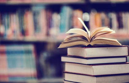 Books On Table Against Shelf In Library