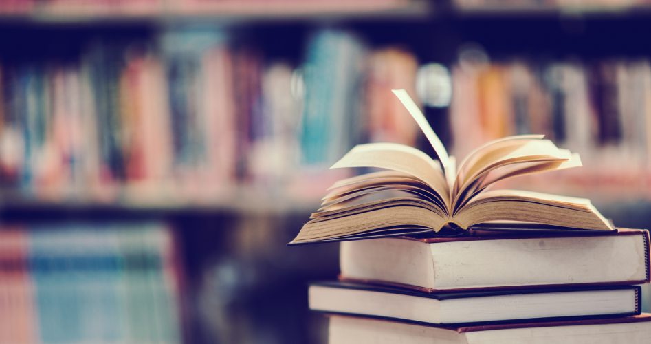 Books On Table Against Shelf In Library